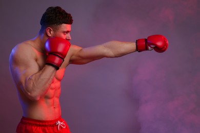 Photo of Man in boxing gloves fighting on color background. Space for text