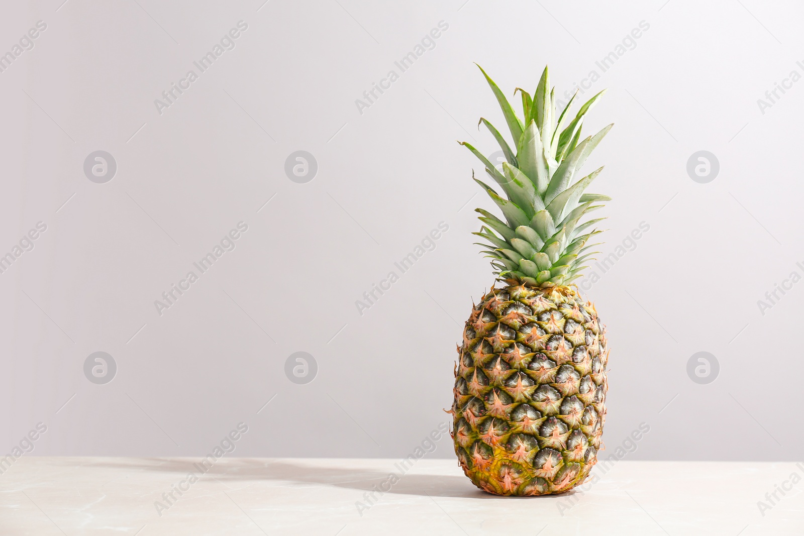 Photo of Fresh pineapple on table against grey wall