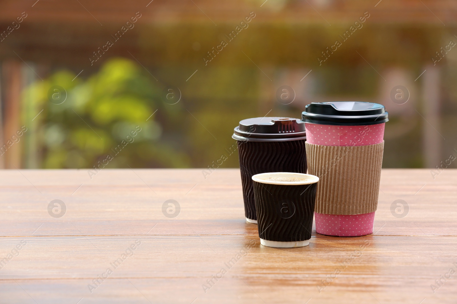 Photo of Cardboard cups of coffee on table against blurred background. Space for text