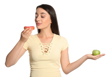 Photo of Concept of choice. Woman eating doughnut and holding apple on white background