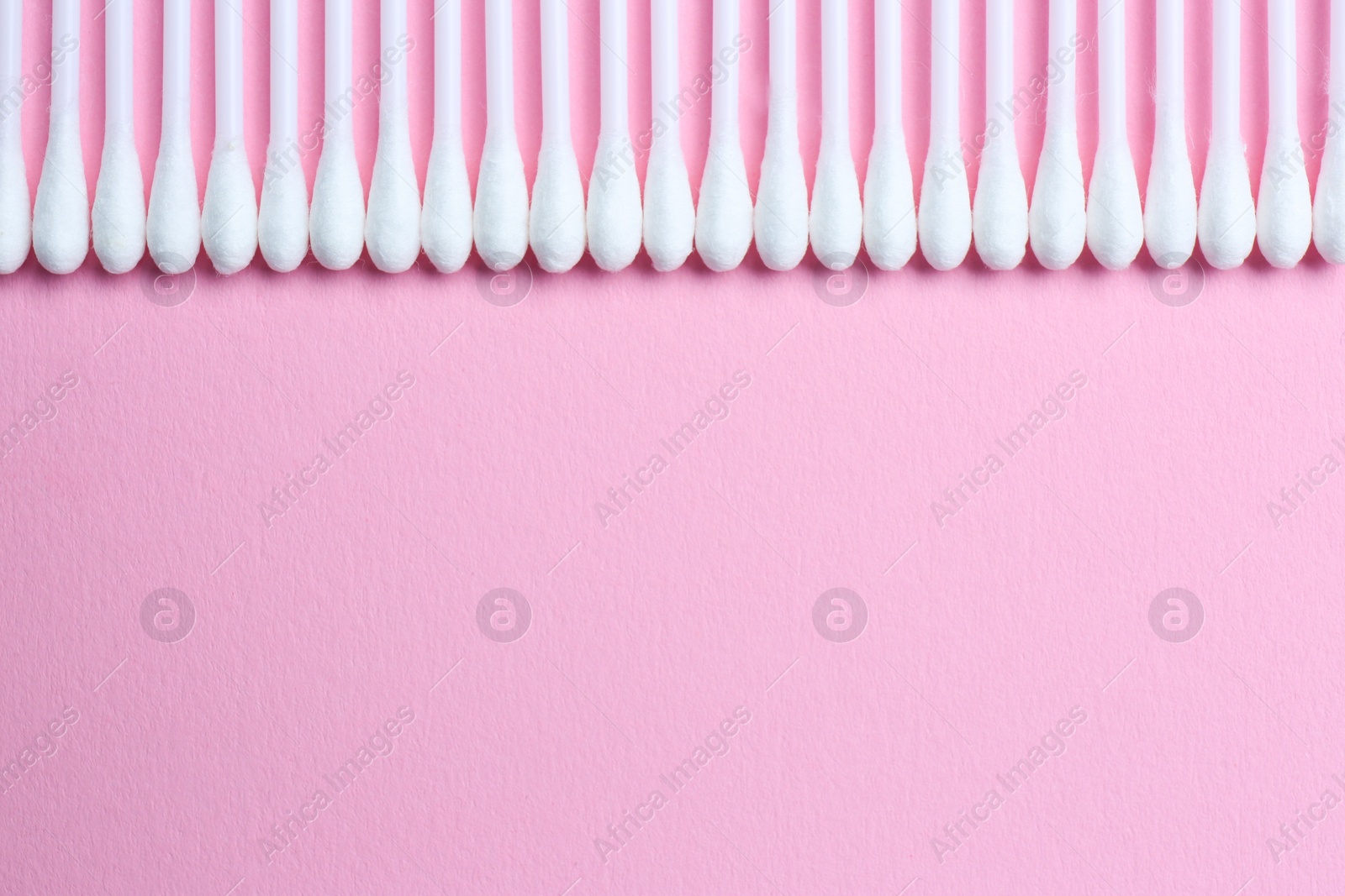 Photo of Many cotton buds on pink background, flat lay. Space for text