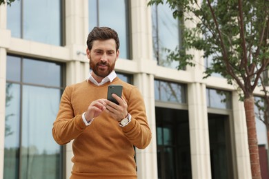 Photo of Handsome man with smartphone on city street, space for text