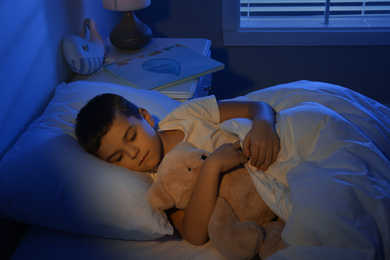 Photo of Little boy sleeping with teddy bear at home. Bedtime