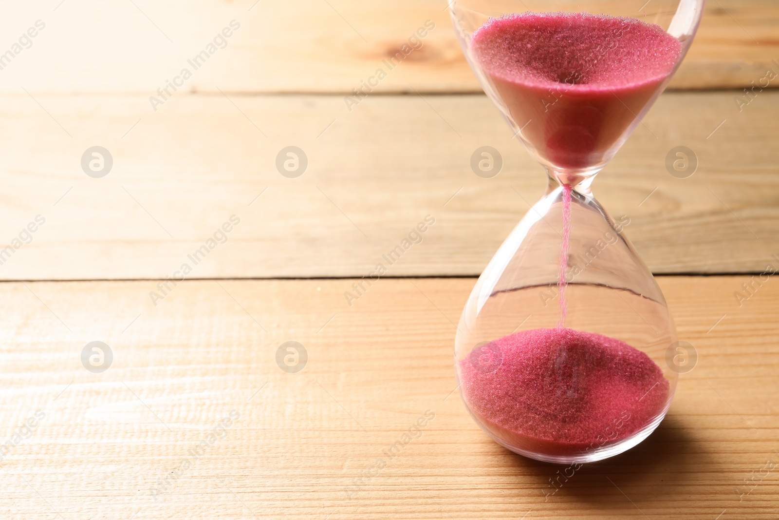 Photo of Hourglass with flowing sand on table. Time management