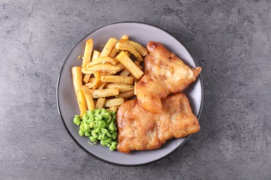 Photo of Tasty fish, chips and peas on grey table, top view