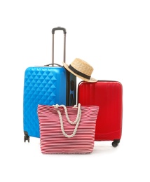 Photo of Packed suitcase with hat and hand-luggage on white background