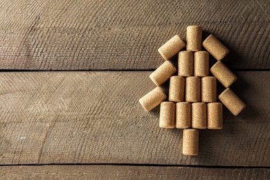 Photo of Christmas tree made of wine corks on wooden table, top view. Space for text