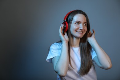 Portrait of beautiful woman with headphones on color background, space for text