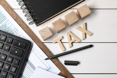 Photo of Word Tax made of letters, cubes, calculator, notebook and documents on white wooden table, flat lay