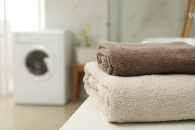 Stack of clean towels on table in laundry room. Space for text