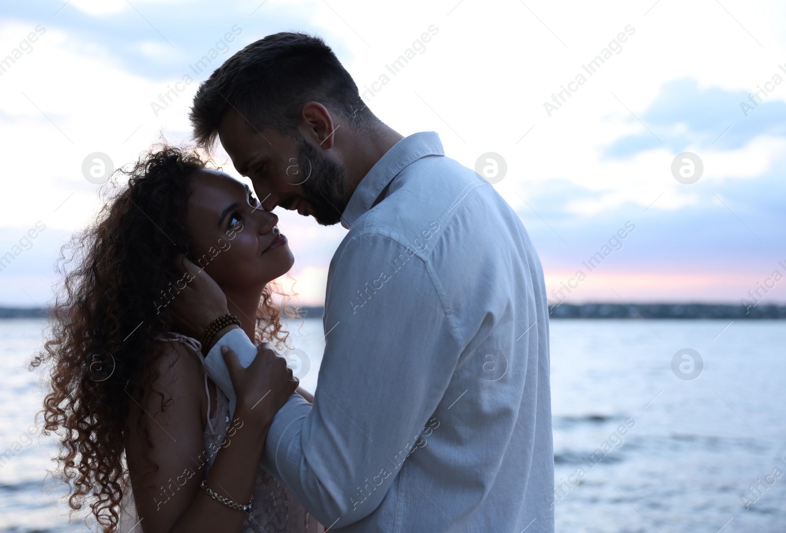 Photo of Lovely couple spending time together near river at sunset