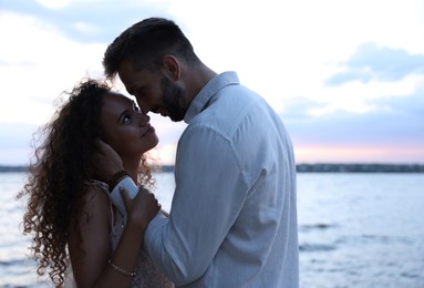 Lovely couple spending time together near river at sunset