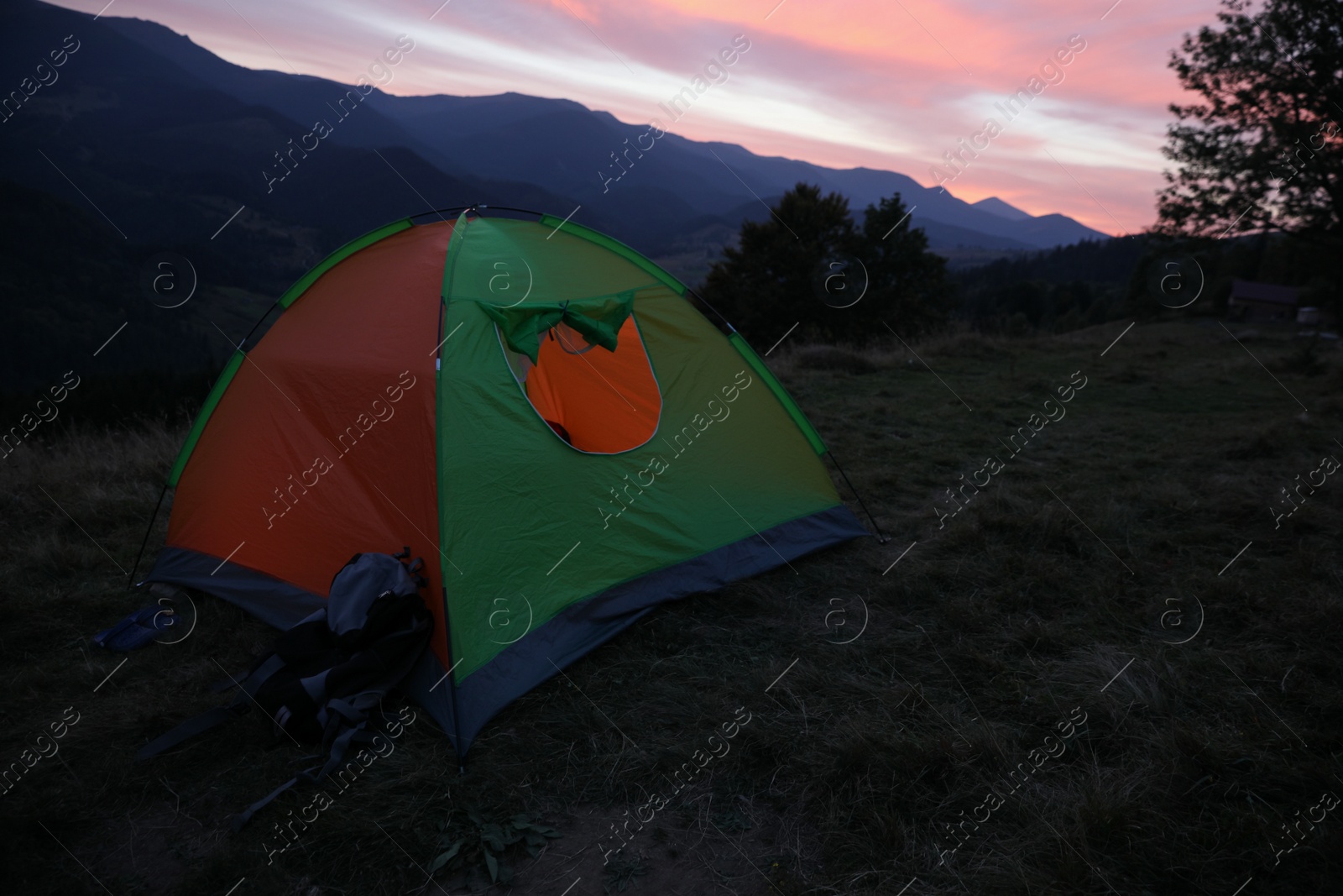 Photo of Colorful camping tent on mountain slope at sunset