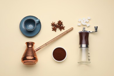 Photo of Flat lay composition with manual grinder and turkish coffee pot on beige background