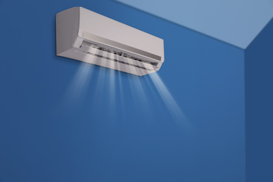 Modern air conditioner on blue wall indoors