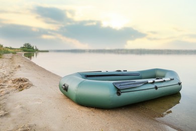 Inflatable rubber fishing boat on sandy beach near river