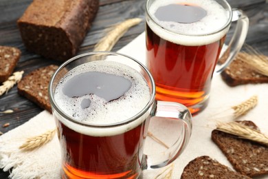 Photo of Mugs of delicious kvass, spikes and bread on table