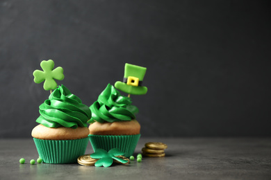 Photo of Delicious decorated cupcakes on grey table, space for text. St. Patrick's Day celebration