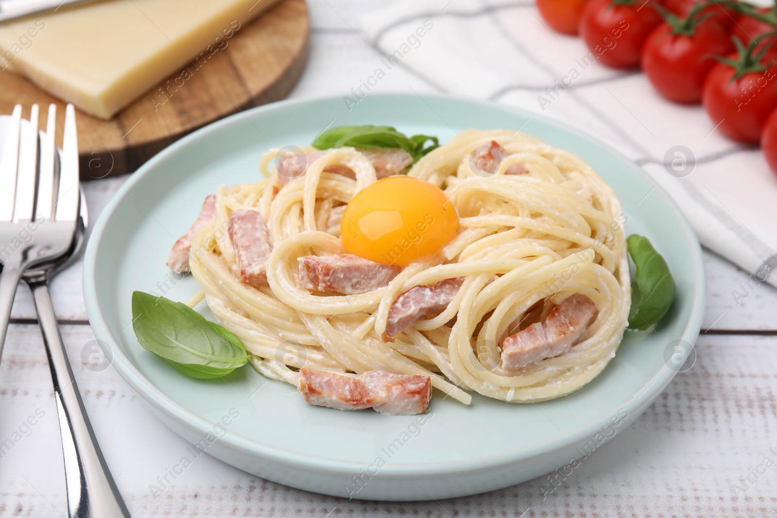 Photo of Delicious pasta Carbonara with egg yolk on white wooden table, closeup