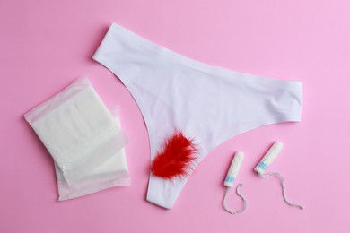 Photo of Menstrual pads, tampons, feather and panties on pink background, flat lay