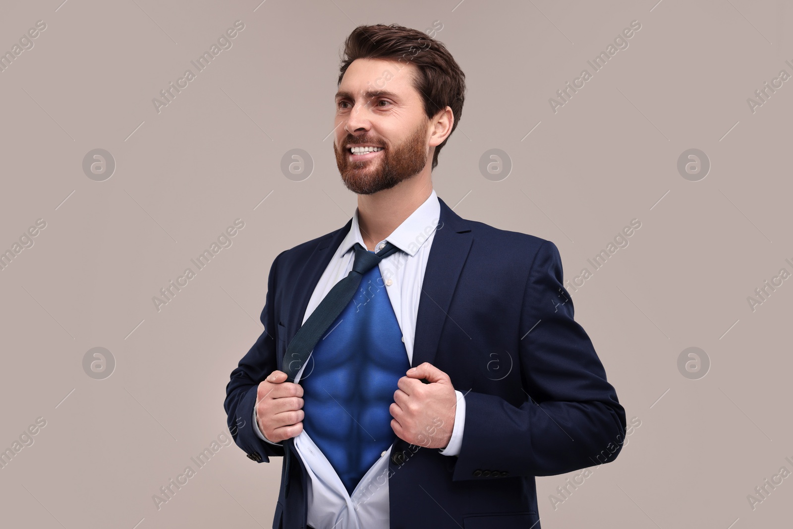 Image of Happy businessman wearing superhero costume under suit on light grey background