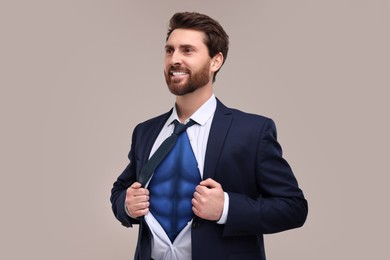 Image of Happy businessman wearing superhero costume under suit on light grey background