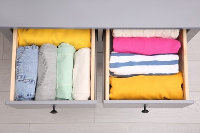 Photo of Open drawers with folded clothes indoors, top view. Vertical storage
