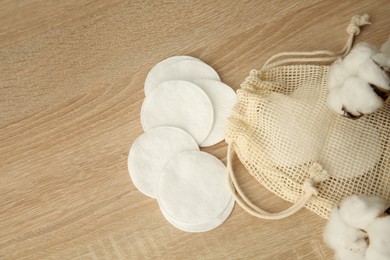 Photo of Cotton pads, bag and flowers on wooden table, flat lay. Space for text