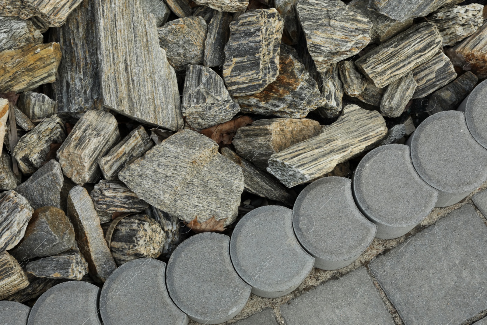 Photo of Decorative stones near pavement as background, top view