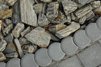 Photo of Decorative stones near pavement as background, top view