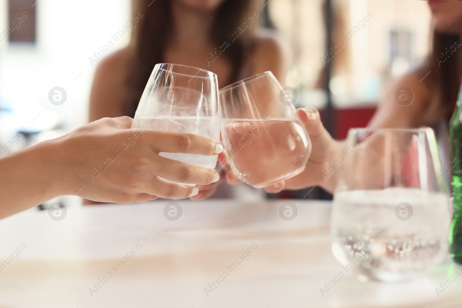 Photo of Young women with glasses of water at table, closeup