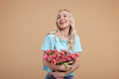 Happy young woman with beautiful bouquet on beige background