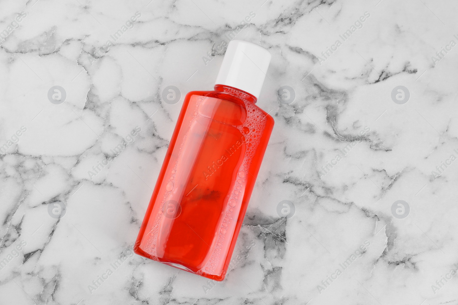 Photo of Fresh mouthwash in bottle on white marble table, top view