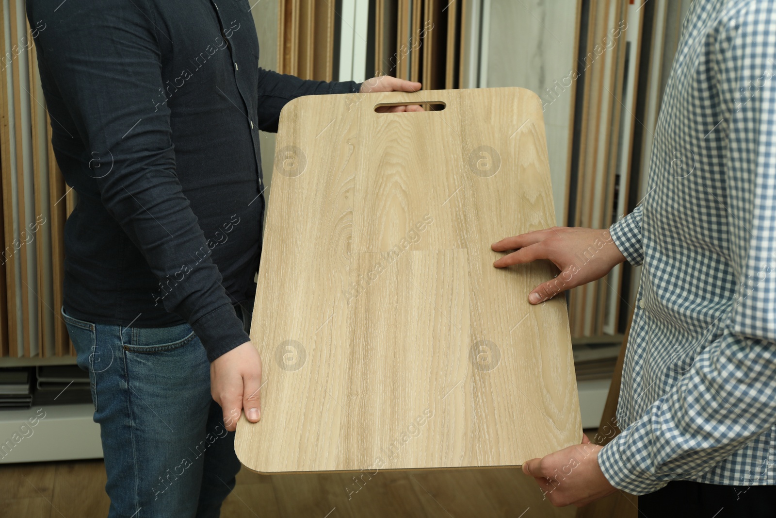 Photo of Men holding sample of wooden flooring in shop, closeup