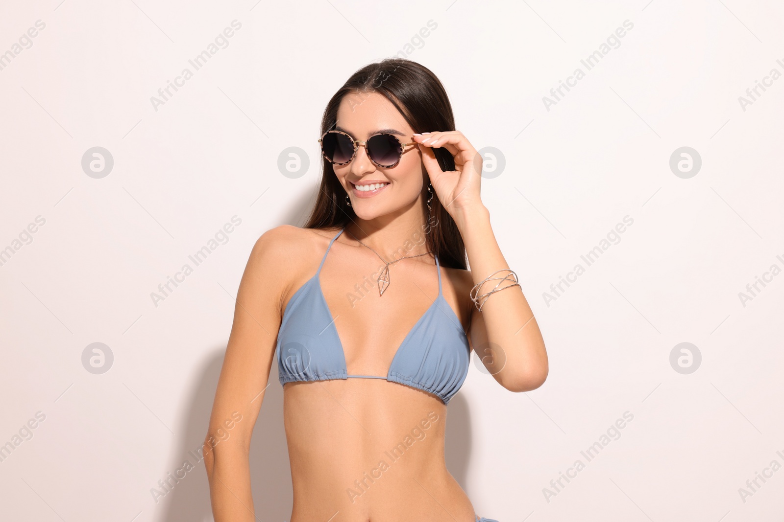 Photo of Young woman in stylish bikini and sunglasses on white background