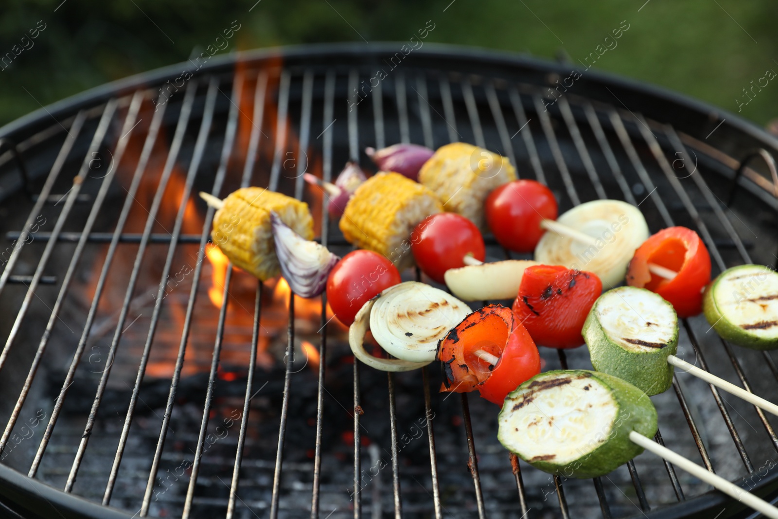 Photo of Skewers with delicious grilled vegetables on barbecue grill, closeup