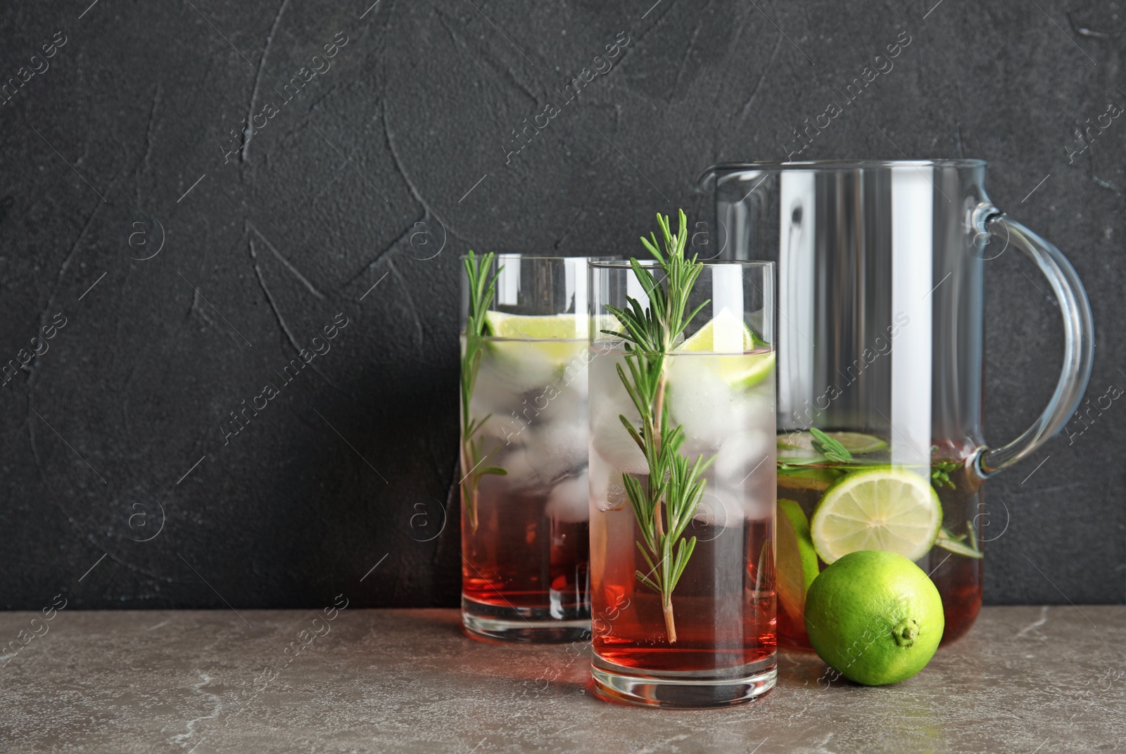 Photo of Glasses of fresh lime cocktail with rosemary and space for text on dark background