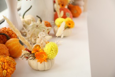 Photo of Small pumpkin with autumn bouquet on white window sill indoors, selective focus. Space for text