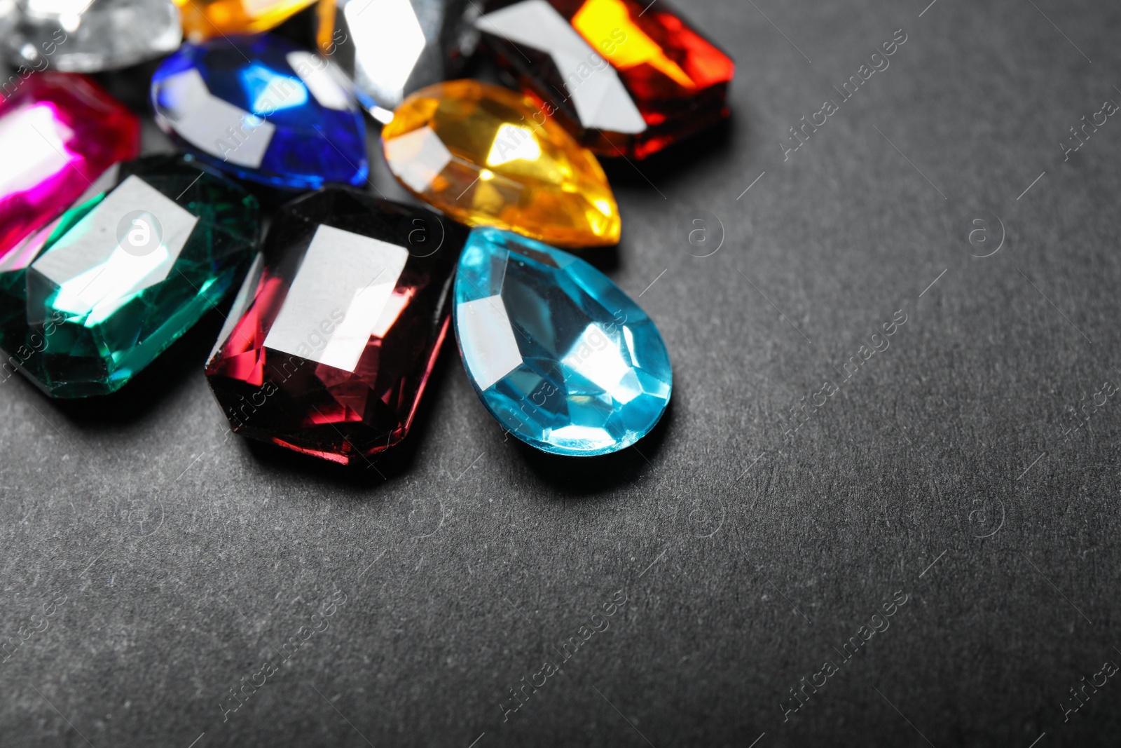 Photo of Pile of different beautiful gemstones on black background, closeup
