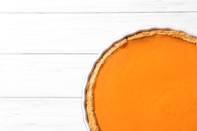 Fresh delicious homemade pumpkin pie on wooden background, top view with space for text