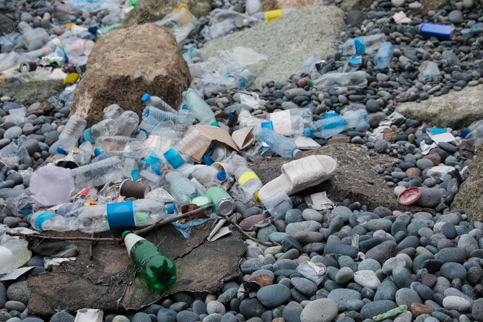 Photo of Garbage scattered on pebbles outdoors. Recycling problem