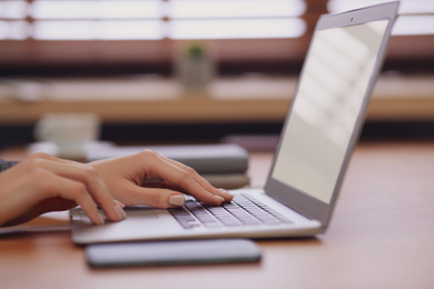 Photo of Woman working on modern laptop at table, closeup