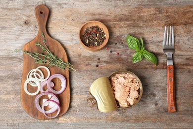 Flat lay composition with canned tuna on wooden background