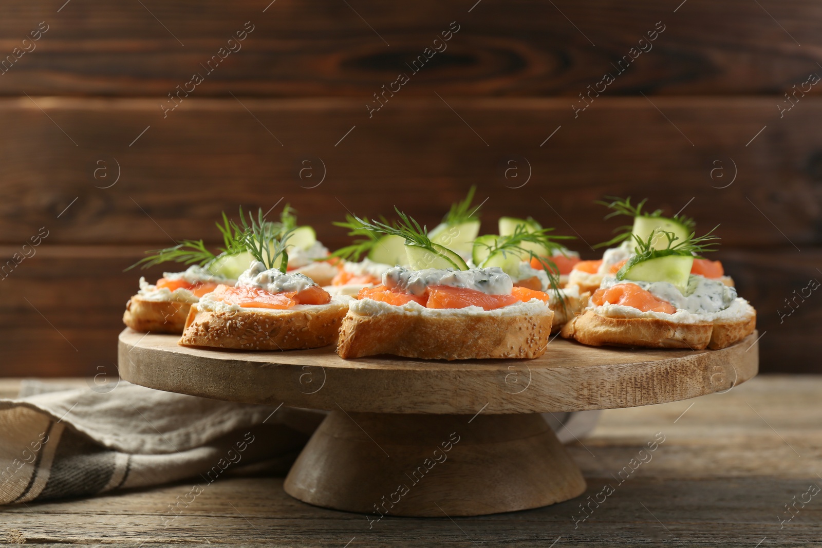 Photo of Tasty canapes with salmon, cucumber, cream cheese and dill on wooden table