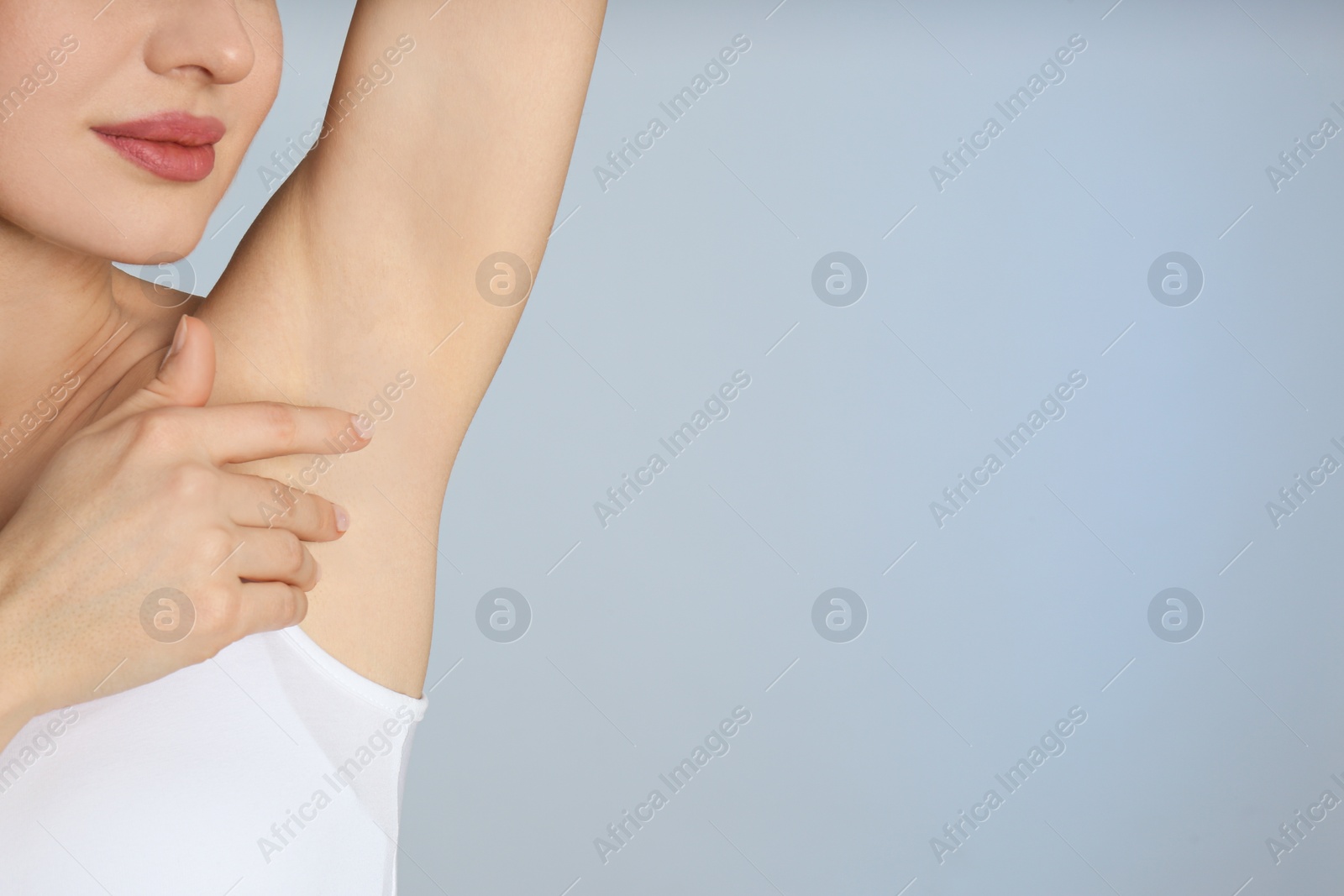 Photo of Young beautiful woman showing armpit with smooth clean skin on light blue background, closeup. Space for text