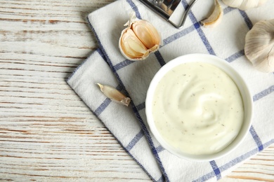 Photo of Flat lay composition with garlic sauce on wooden background. Space for text