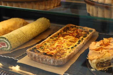 Photo of Delicious quiche with cheese and broccoli on counter in bakery shop, closeup