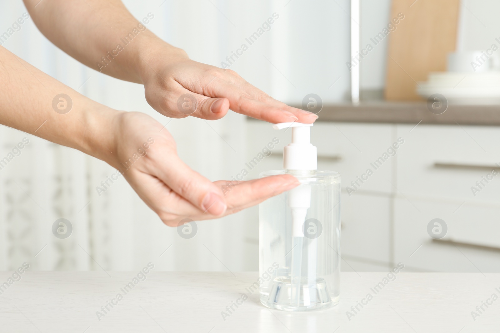 Photo of Woman applying antiseptic gel on hand indoors, closeup