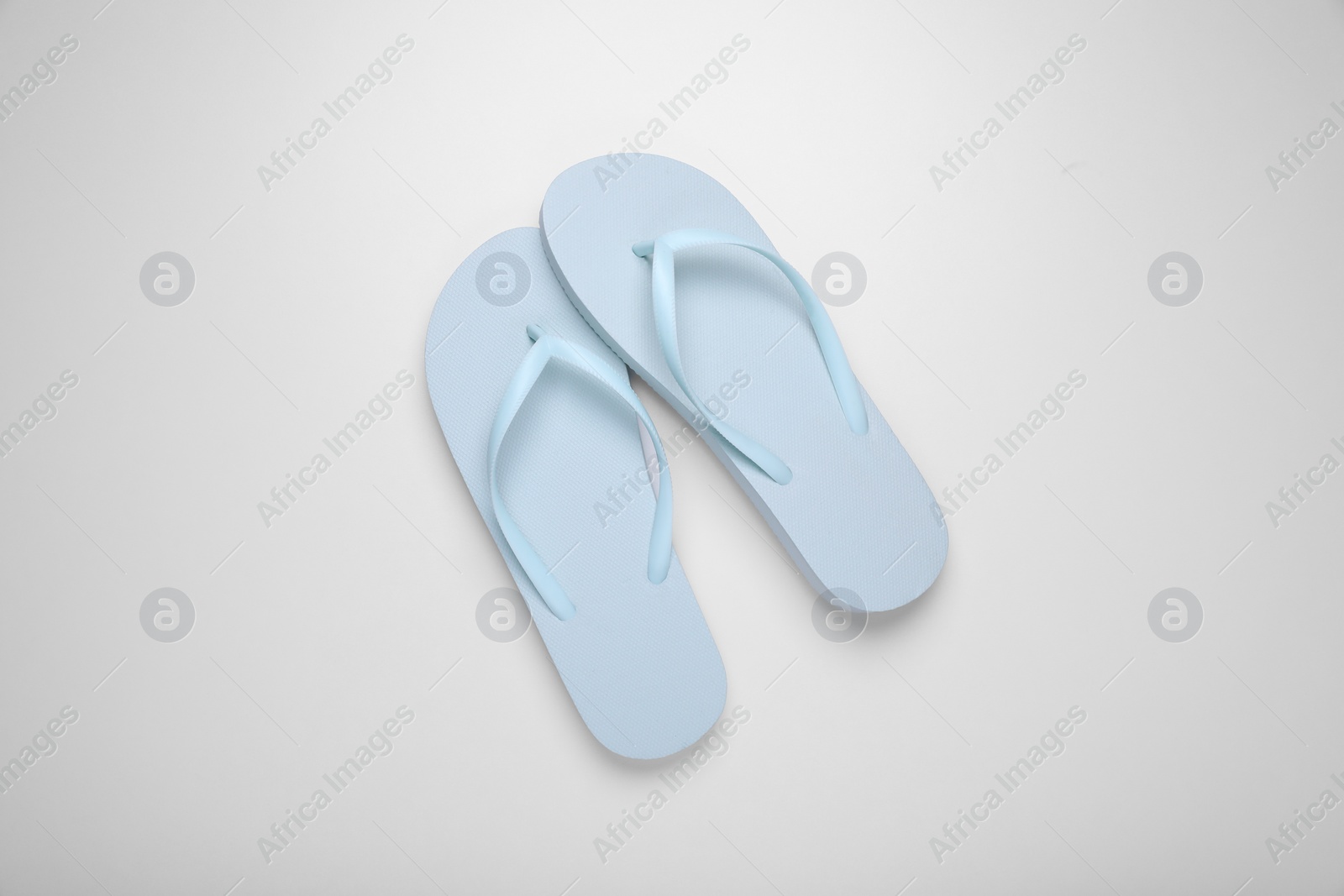 Photo of Light blue flip flops on white background, top view