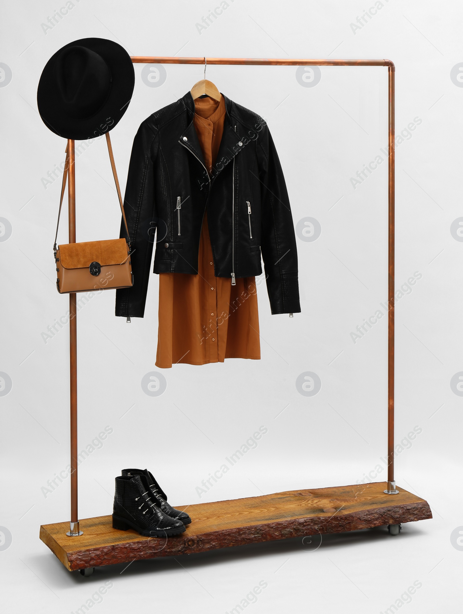 Photo of Wooden rack with stylish clothes and ankle boots on white background